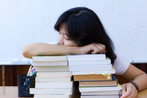 Tired college student in uniform with stack of books