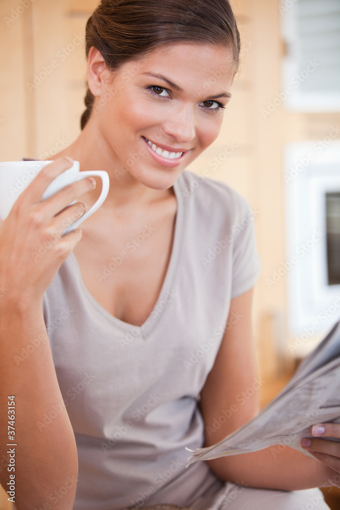 Smiling woman reading the news while drinking coffee Smiling woman reading the news while drinking coffee