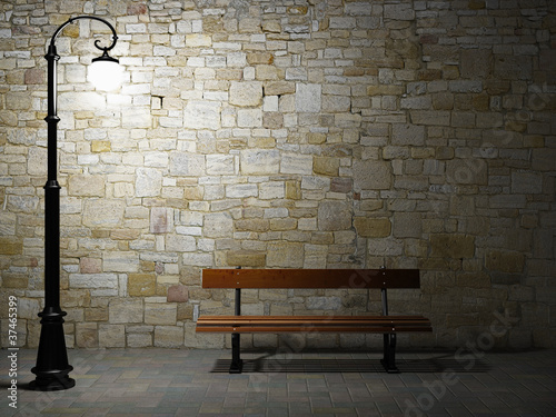 Illuminated brick wall with old fashioned street light and bench