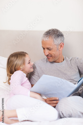 Portrait of a smiling father reading a story to his daughter