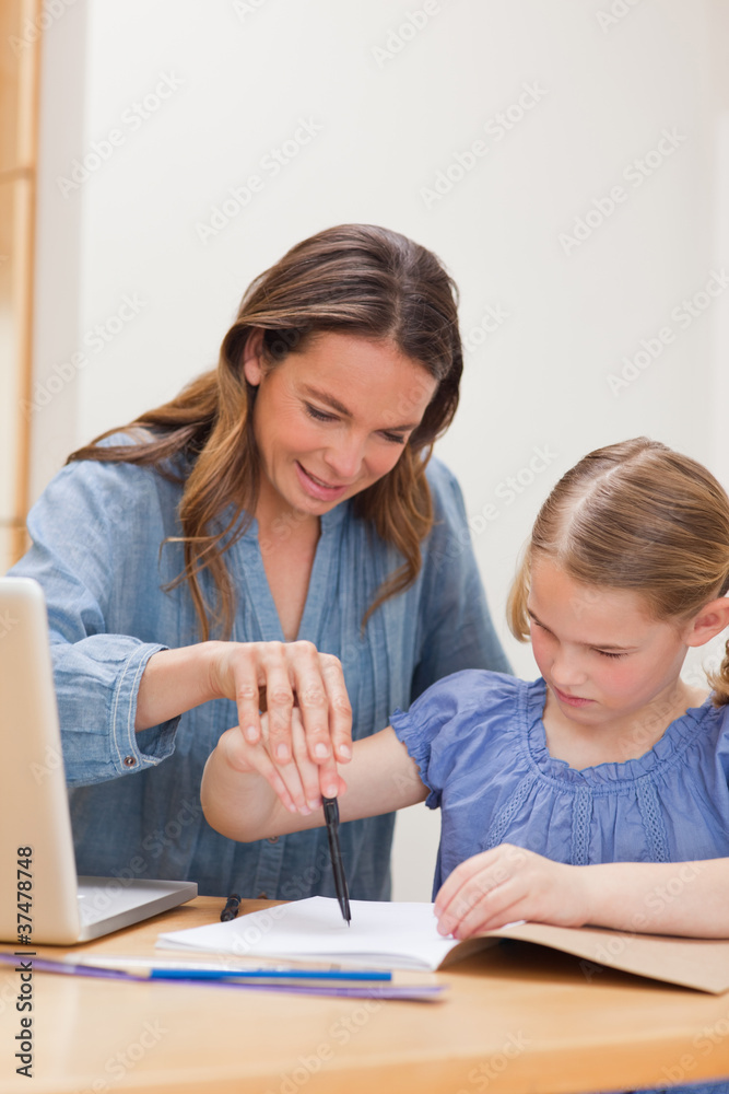 Portrait of a mother helping her daughter doing her homework Portrait of a mother helping her daughter doing her homework