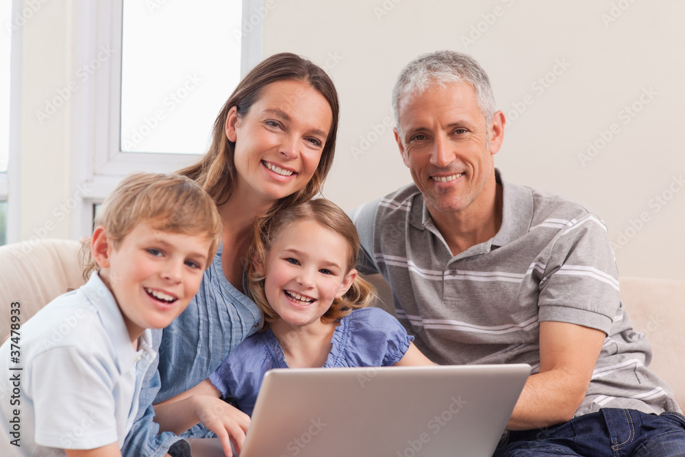 Happy family sitting on a couch using a laptop Happy family sitting on a couch using a laptop