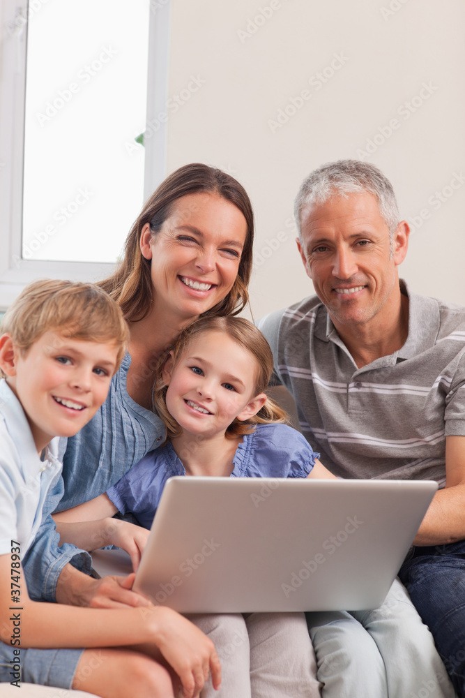 Portrait of a family sitting on a couch using a laptop Portrait of a family sitting on a couch using a laptop