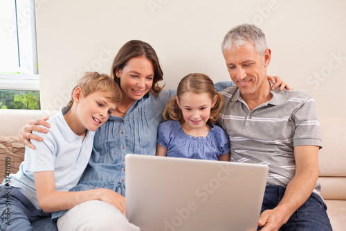 Family sitting on a sofa using a notebook