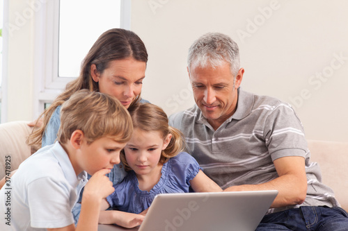 Happy family sitting on a sofa using a notebook