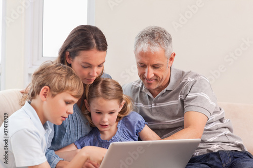 Happy family sitting on a sofa using a laptop