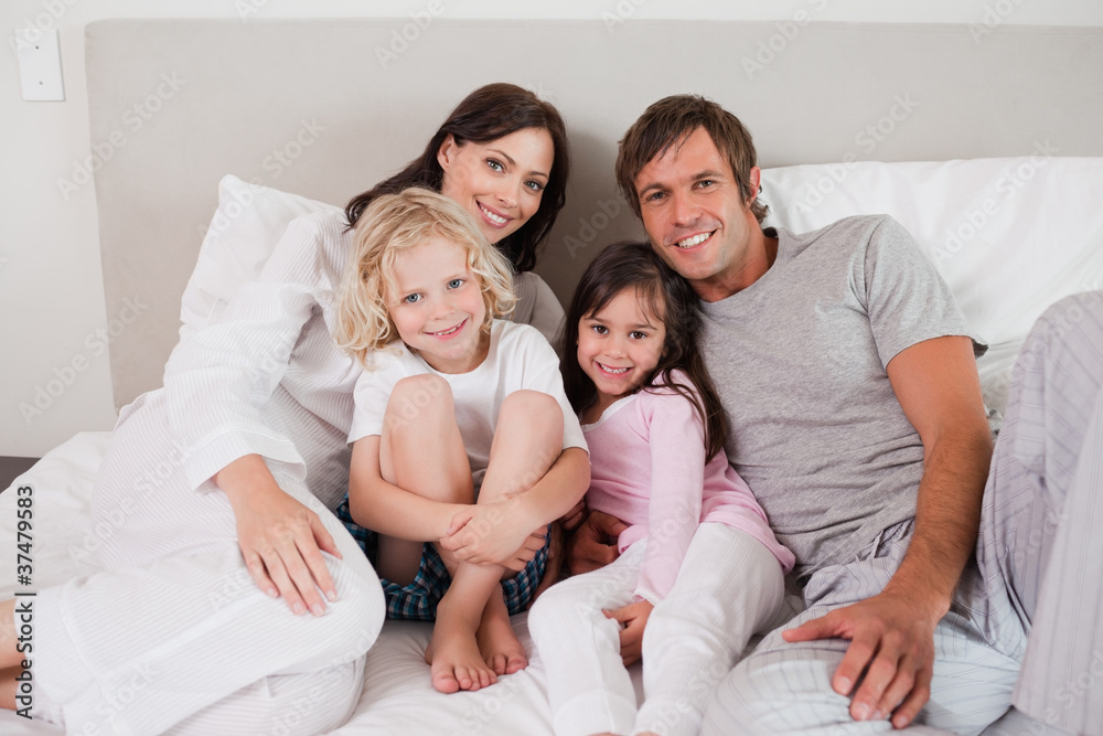 Smiling family posing on a bed Smiling family posing on a bed