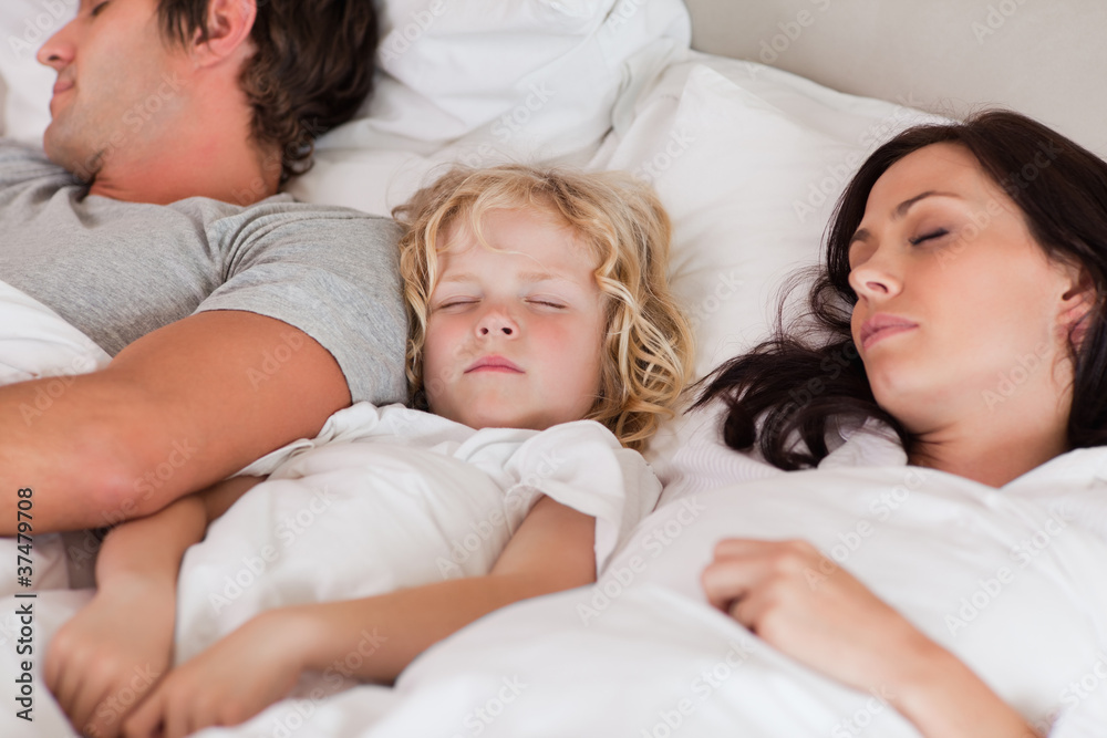 Boy sleeping between his parents