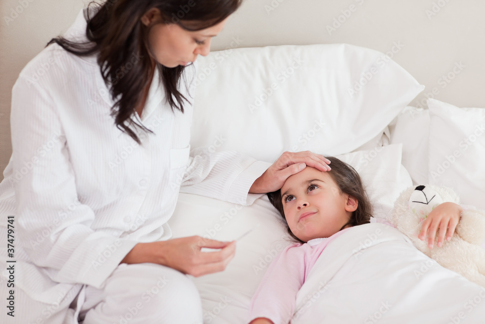 Mother checking on her daughter's temperature Mother checking on her daughter's temperature