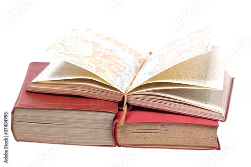 three old books with an open map on white