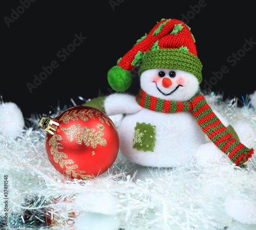 Toy snowman with festive red ball on a black