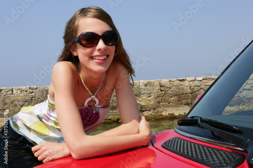 Young woman leaning against a car
