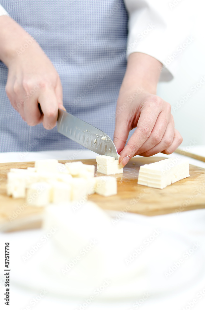 Woman's hands cutting feta cheese