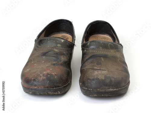 Front view of old dirty clogs on a white background