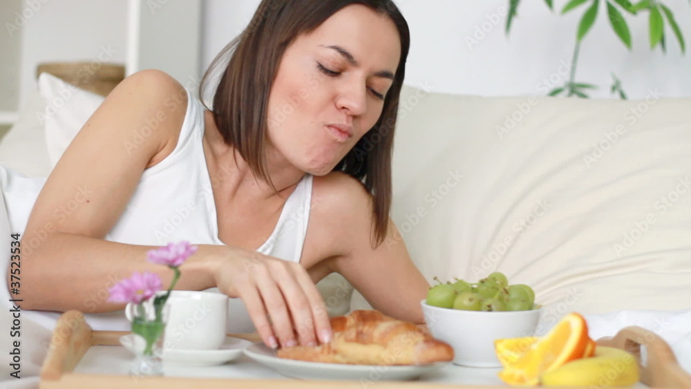 Attractive happy woman eating breakfast in bed Attractive happy woman eating breakfast in bed