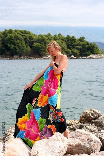 Young pregnant smiling woman dressed in colored pareo looks down
