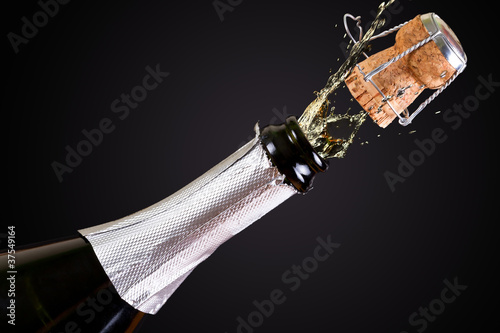 Картината върху платно Bottle of champagne with splashes over black background