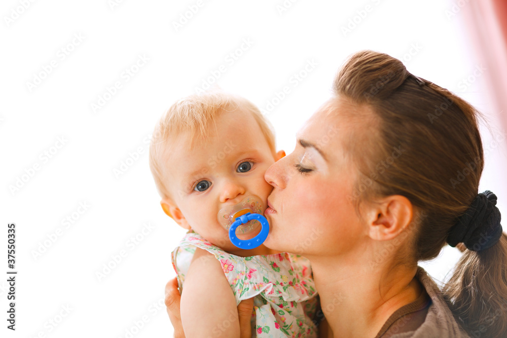 Young mother kissing baby with soother Young mother kissing baby with soother