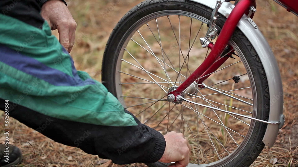 Man's hands pump up a bicycle wheel
