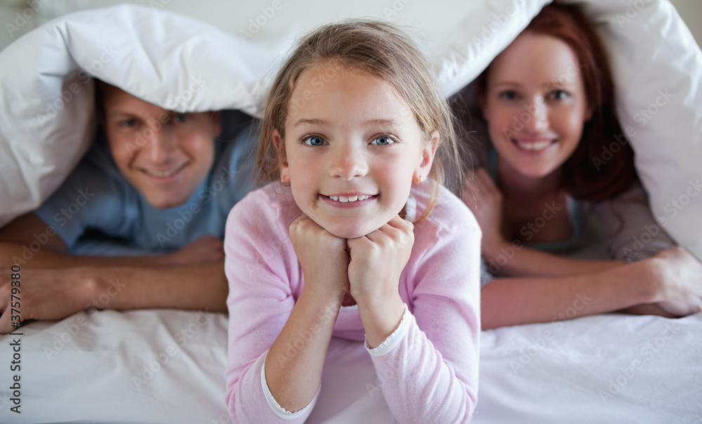 Girl under bed cover with parents Girl under bed cover with parents