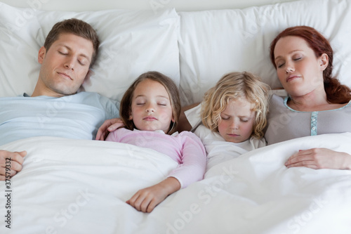 Adorable family sleeping in the bed together © WavebreakmediaMicro