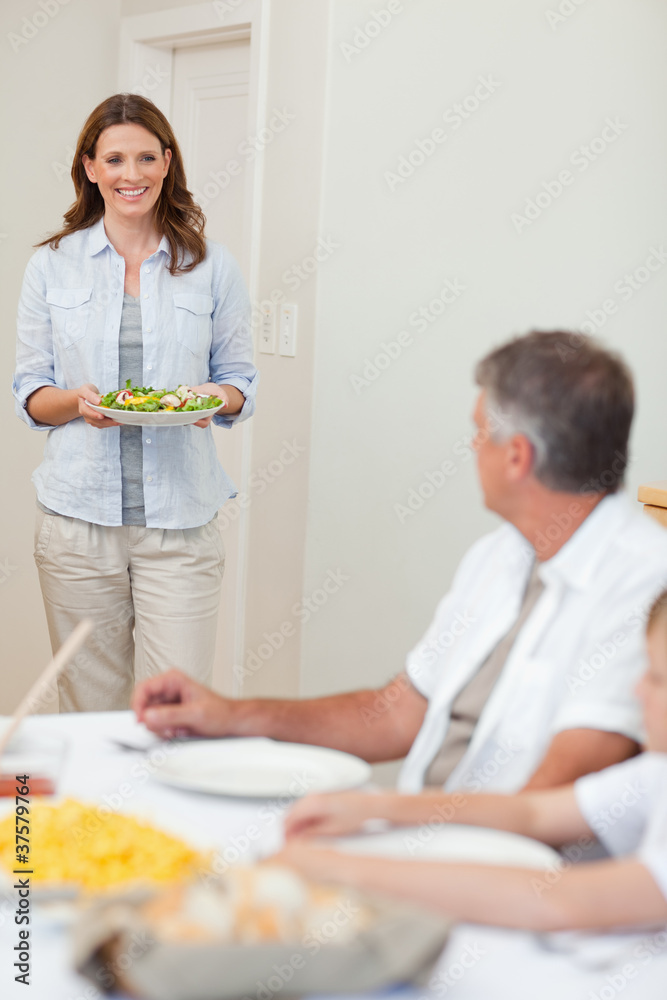 Mother bringing salad to the dinner table