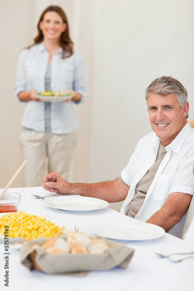 Man waiting for his wife to bring salad to the table