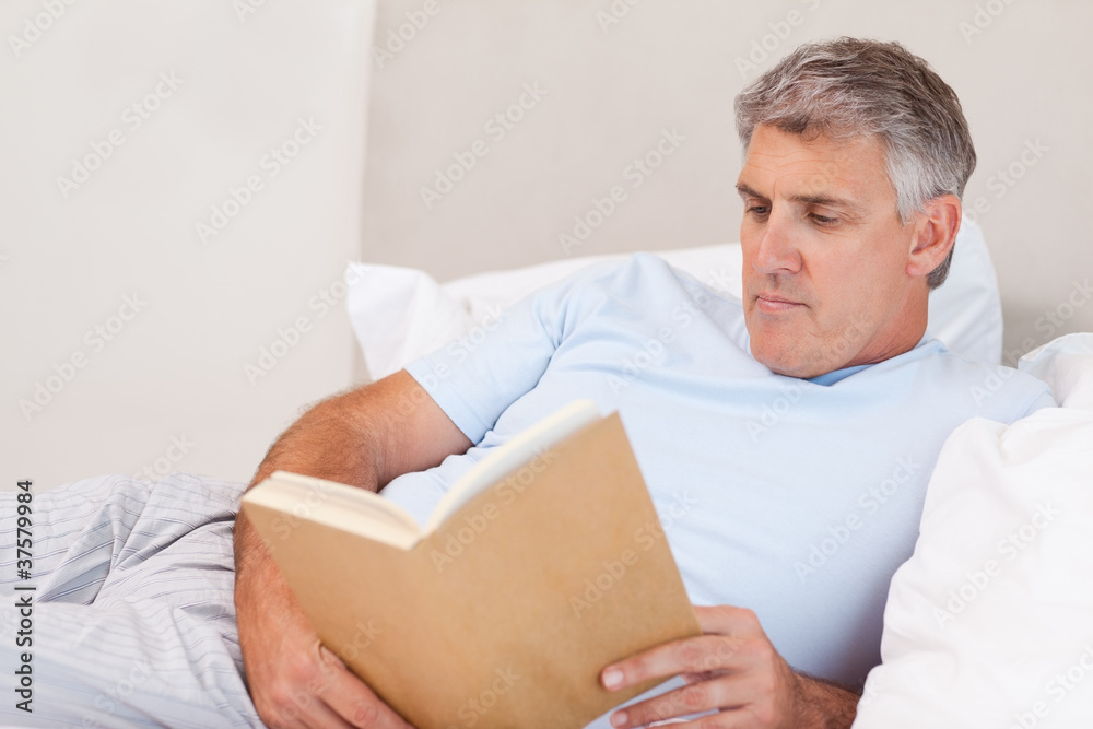 Mature man reading book in bed Mature man reading book in bed