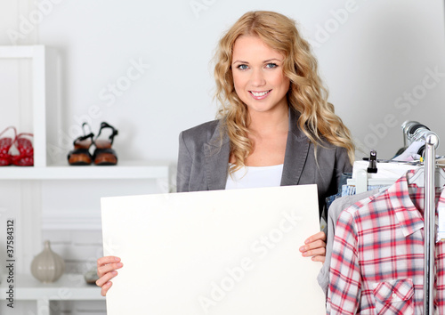 Beautiful woman in garment store holding message board photo