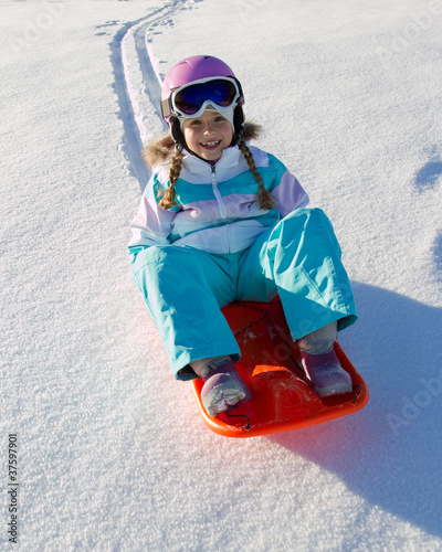 Fotografie Happy winter - little girl  sledging downhill
