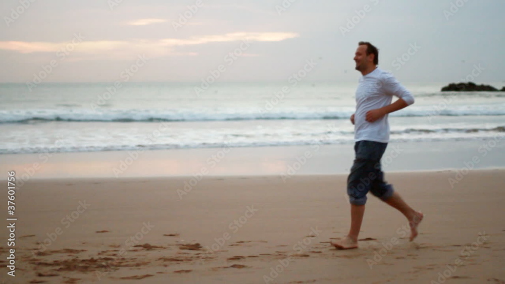 Happy man running and turning around at the beach, slow motion Happy man running and turning around at the beach, slow motion
