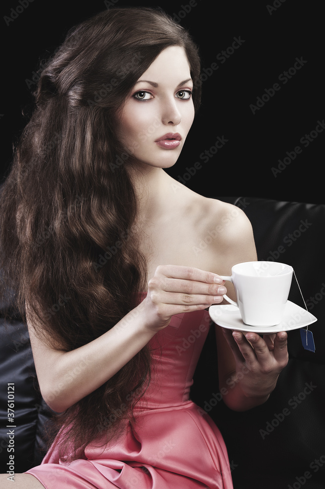 sophisticated lady drinkig tea, she takes a cup of tea with both sophisticated lady drinkig tea, she takes a cup of tea with both