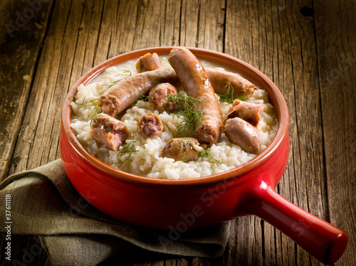 Fotografia risotto with sausage over red casserole