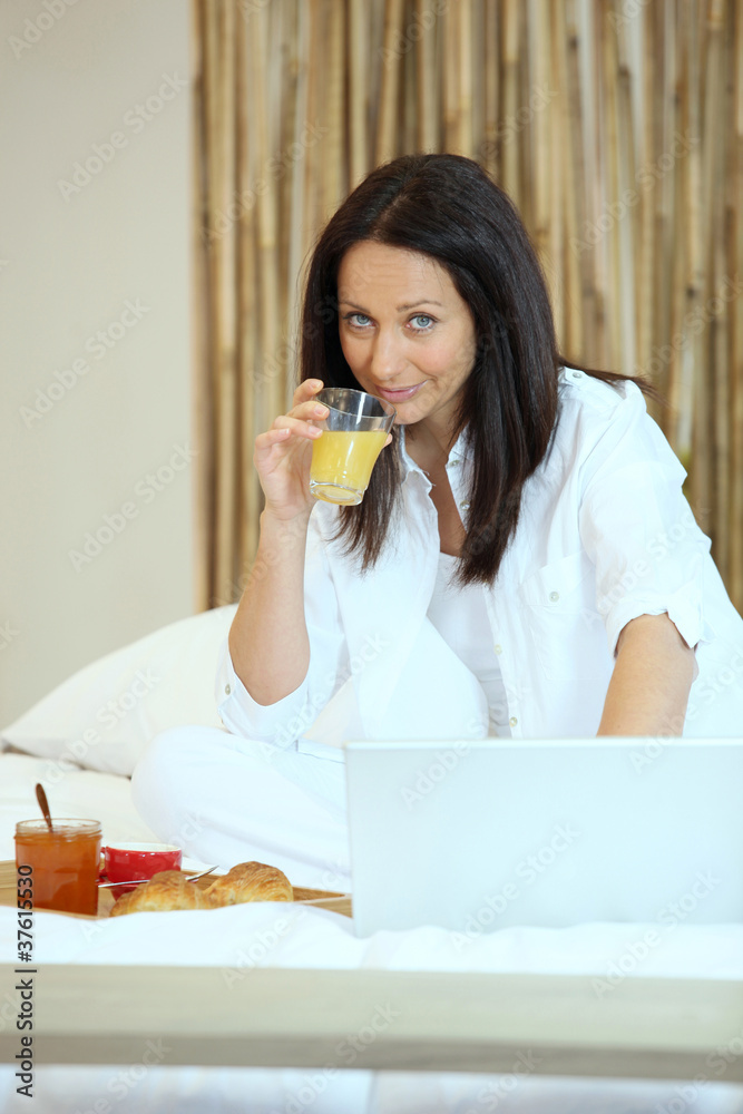 Woman in bed with breakfast and her laptop Woman in bed with breakfast and her laptop