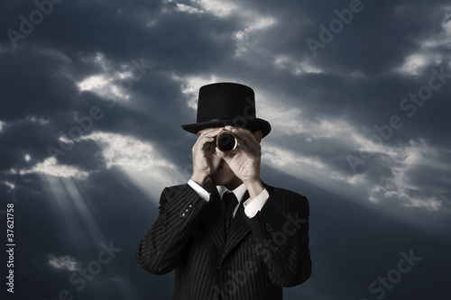 business man looks through a telescope in darkness