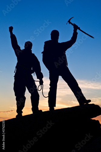 Silhouette of two climbers with hands up