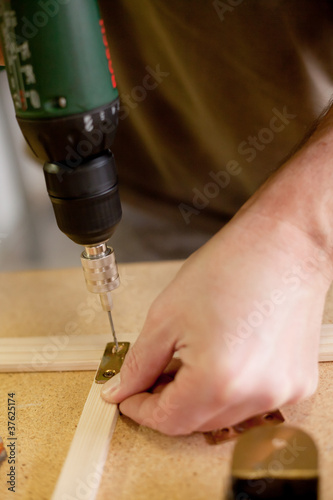 drilling a hole in the wood with an electric drill