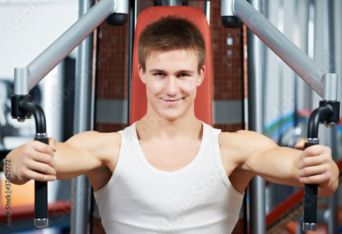 positive man at chest exercises machine