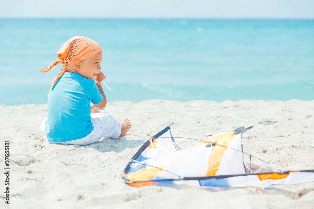 Cute boy on beach playing with a colorful kite Cute boy on beach playing with a colorful kite