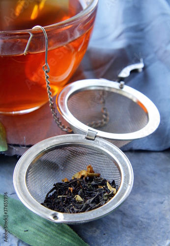 Fotografie tea strainer with a fragrant black tea and cups
