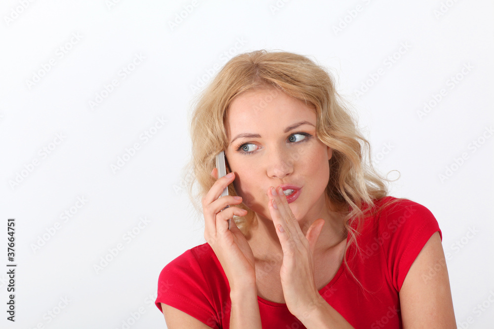 Blond woman with red shirt telling secret on the phone Blond woman with red shirt telling secret on the phone