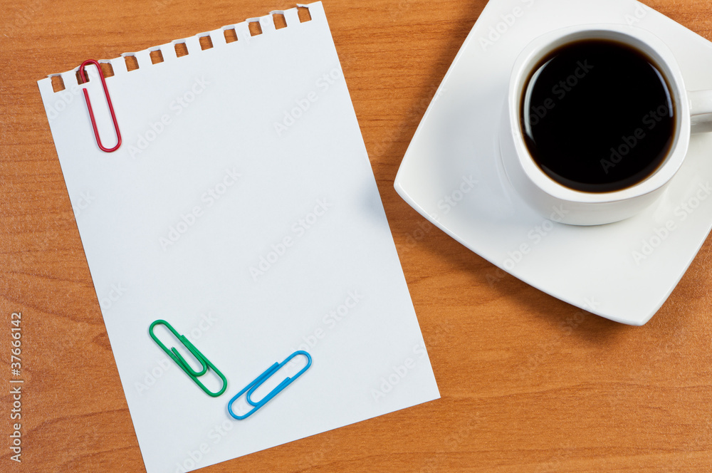 Cup coffee on table and torn sheet with clips. Cup coffee on table and torn sheet with clips.