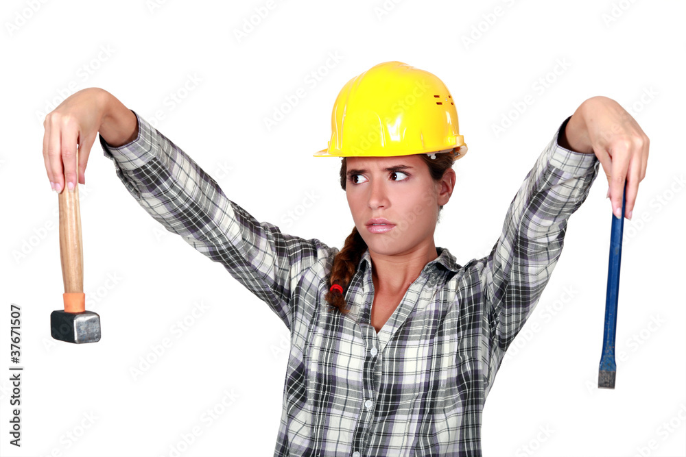 Apprehensive tradeswoman holding a hammer and chisel