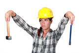 Apprehensive tradeswoman holding a hammer and chisel