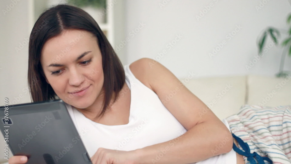 Happy woman with digital tablet lying in bed Happy woman with digital tablet lying in bed