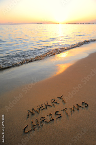 Merry Christmas handwritten in sand on a beautiful beach