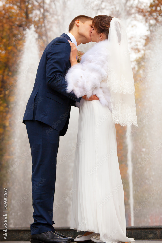 Bride and groom kissing against fountain Bride and groom kissing against fountain