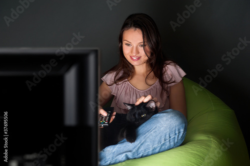 Happy young woman swapping the TV channels , relaxed on the bean