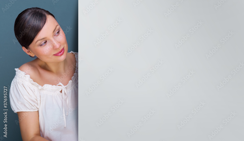 Closeup of young, pretty woman standing near huge blank board an Closeup of young, pretty woman standing near huge blank board an