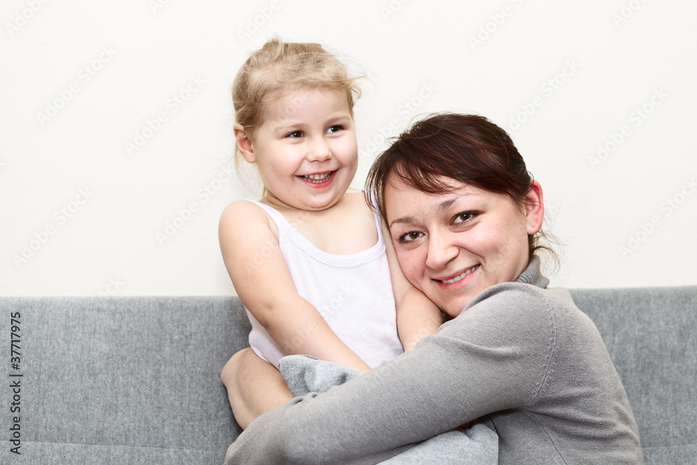 Mother and her little daughter sitting and couch and hugging Mother and her little daughter sitting and couch and hugging